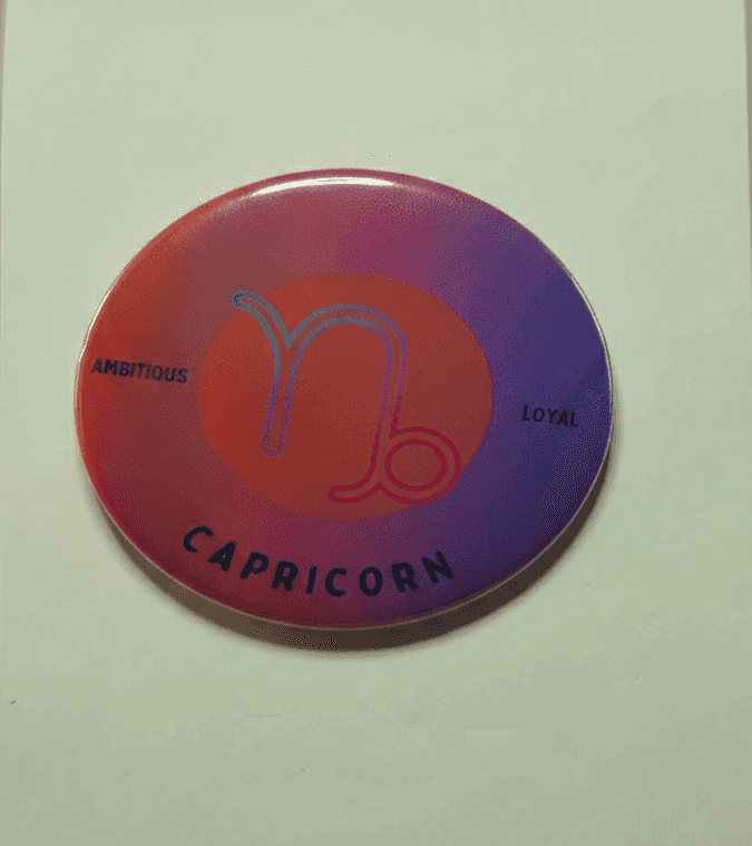 Capricorn zodiac badge with red-purple ombre background, bold Capricorn symbol, and traits 'Ambitious' and 'Loyal' in black text