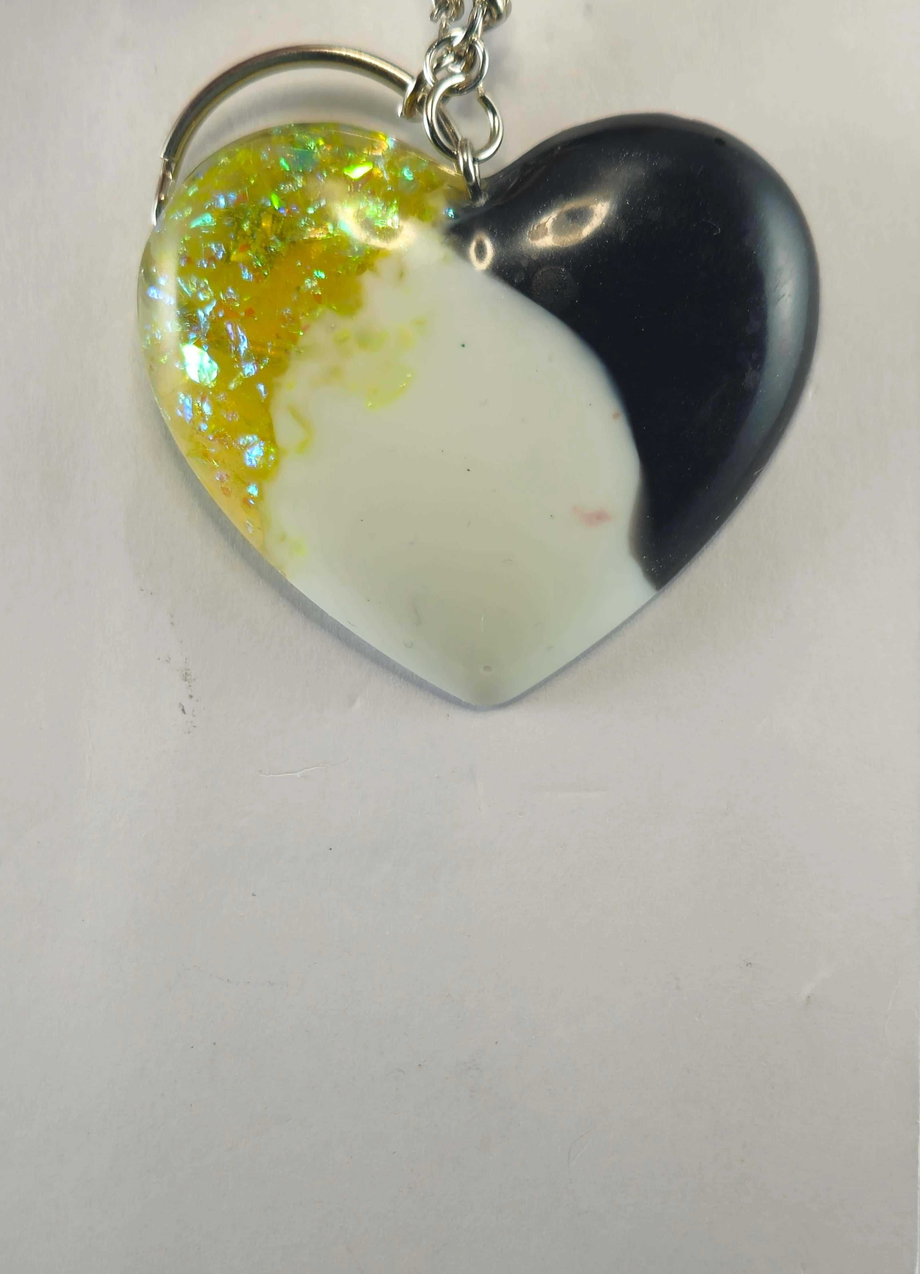 Heart-shaped keychain with black and white marble, iridescent yellow flakes, and a silver chain