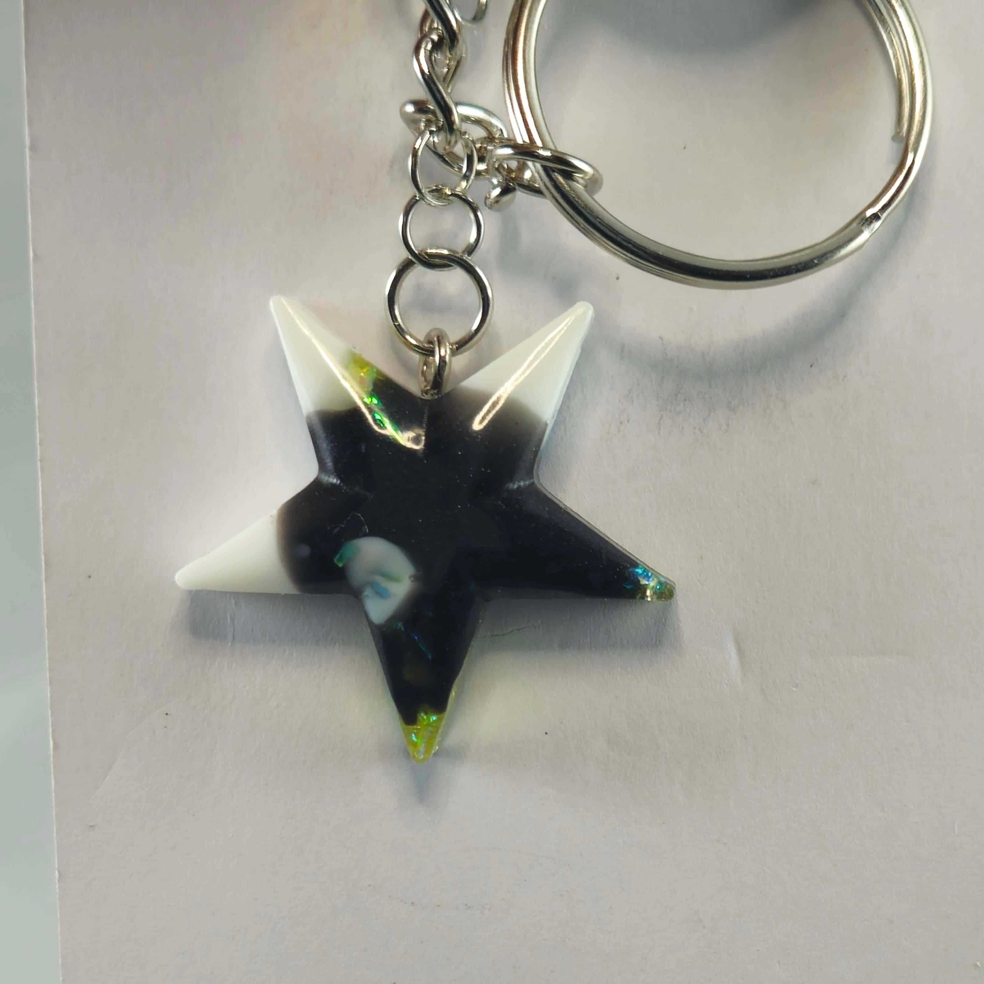 Iridescent star-shaped keychain with black and white marbled accents and green holographic details