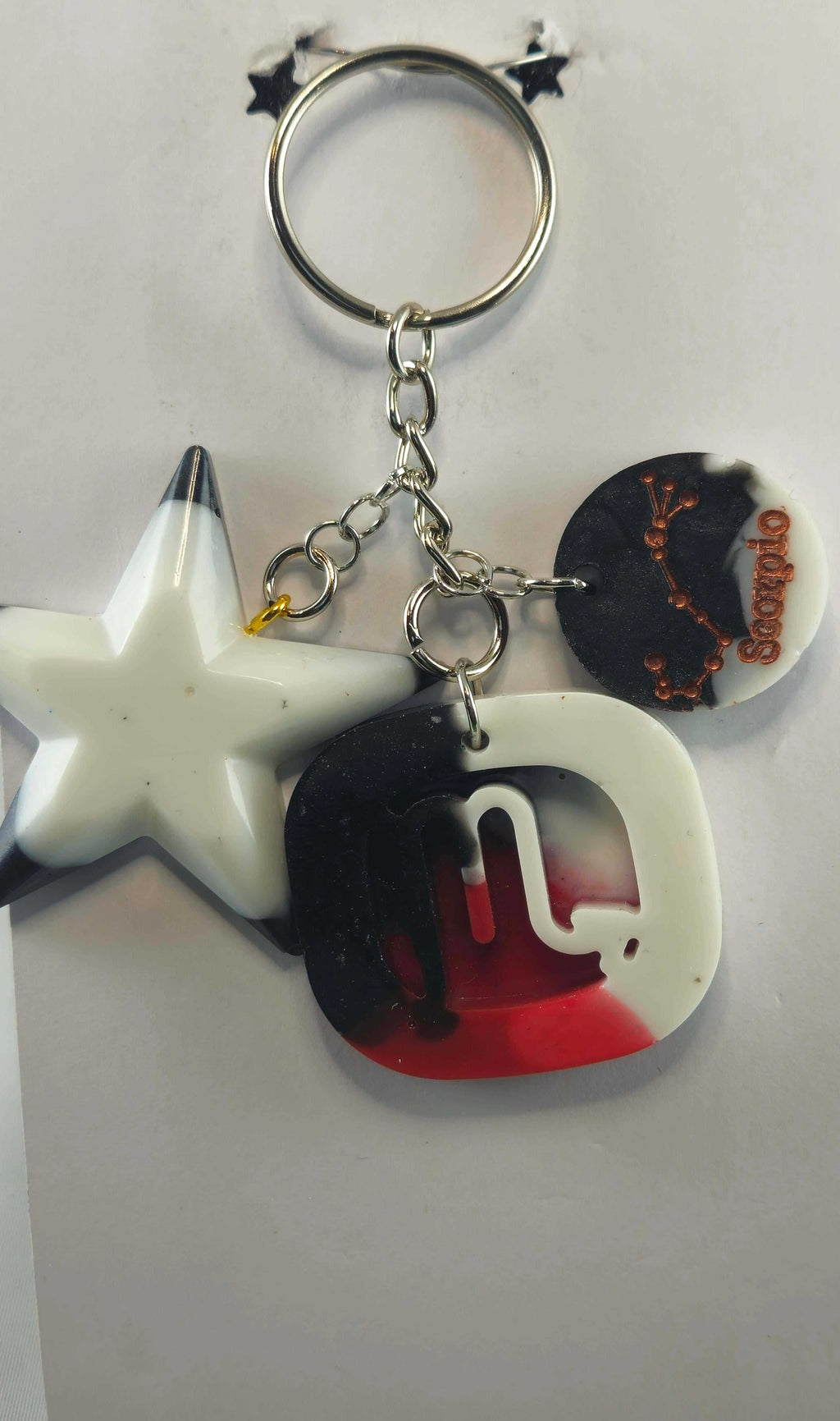 Black, white, and red acrylic letter keychain with a star and zodiac charm