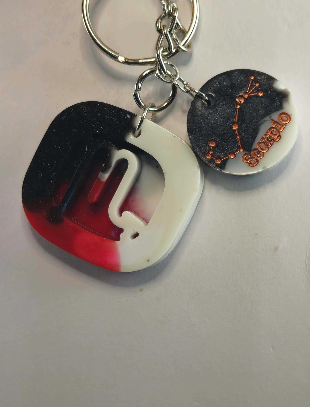 Black and white resin keychain with red and black abstract design
