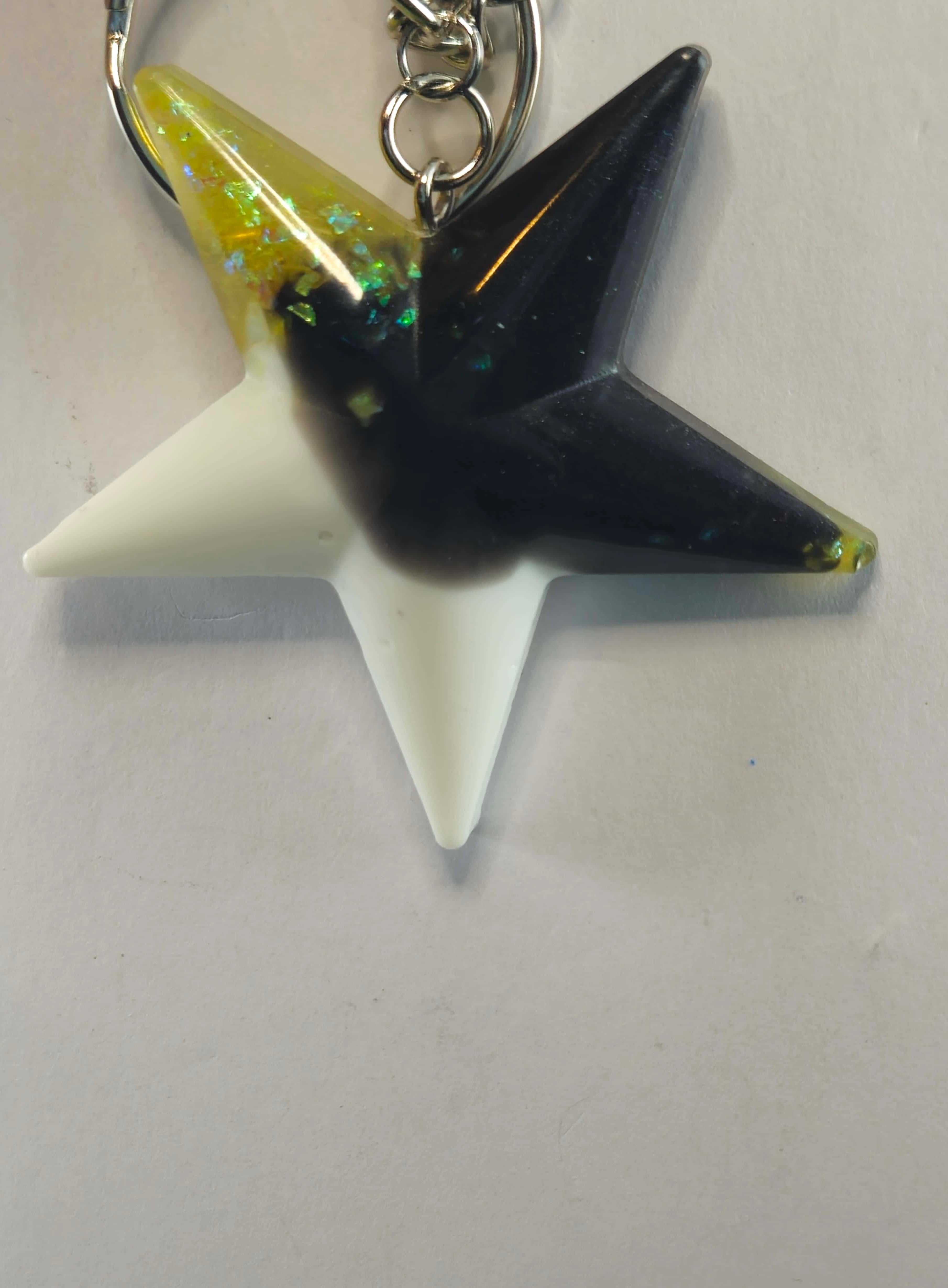 Star-shaped keychain with black, white, and iridescent yellow sections, attached to a metal keyring