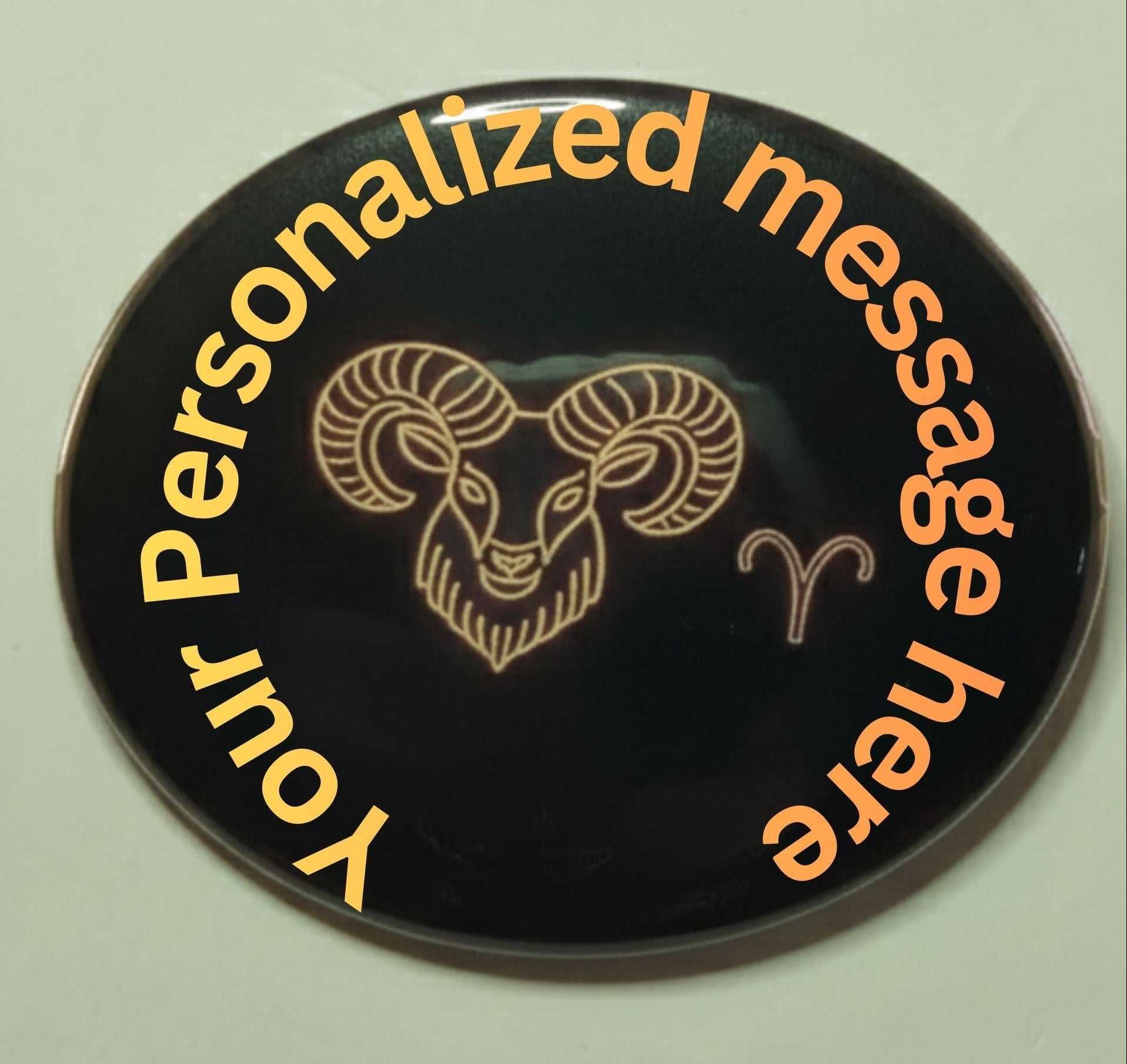 Black pinback button with gold ram's head design and orange text